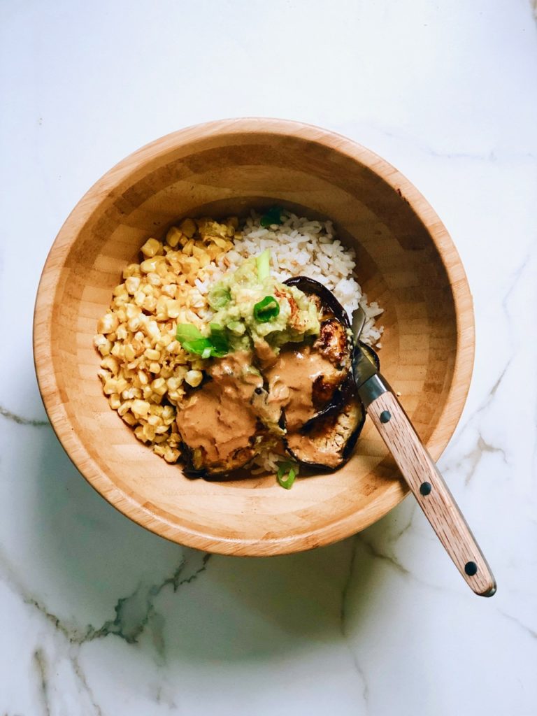 Vegan bowl met met geroosterde mais, aubergine, avocadocrème & sesamsaus